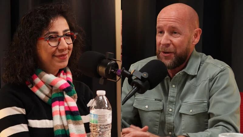Two hosts of Why Not Here talking across the studio table, mics on boom arms